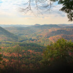 Autumn view framed by hemlock trees of the rolling hills of the West River valley in southern Vermont